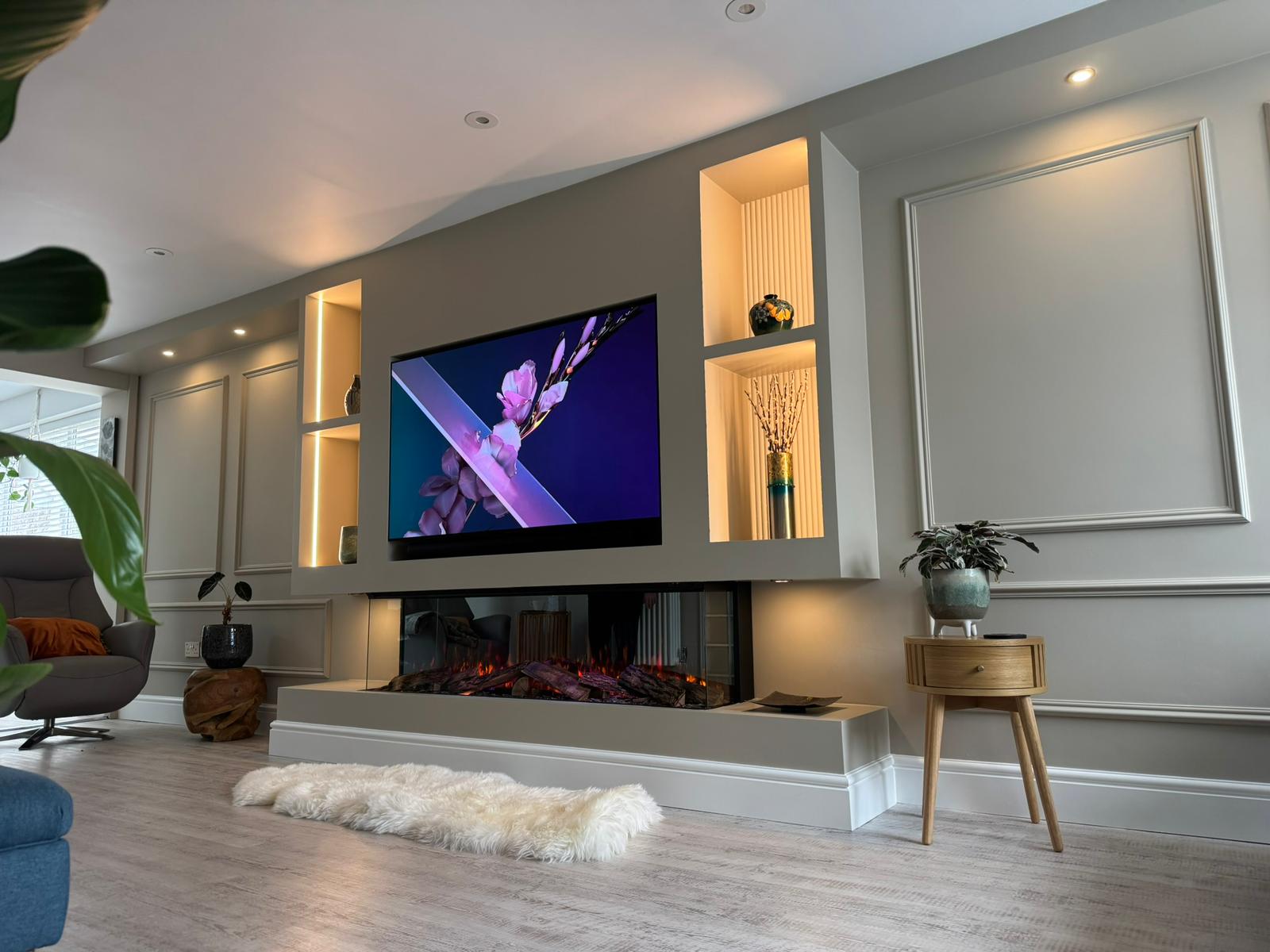 A finished media wall with warm linear fireplace and ambient halo lighting in a modern Warwickshire living room